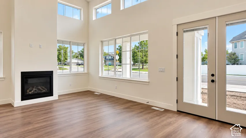Double-height ceilings, wood-finish flooring, built-in fireplace with black surround, grid-pane windows, and dual-pane glass exterior door
