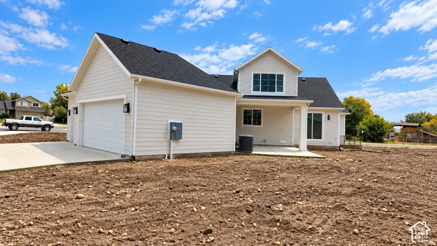 Exterior view featuring horizontal siding, a multi-gabled roofline, concrete driveway, attached garage, and covered concrete patio