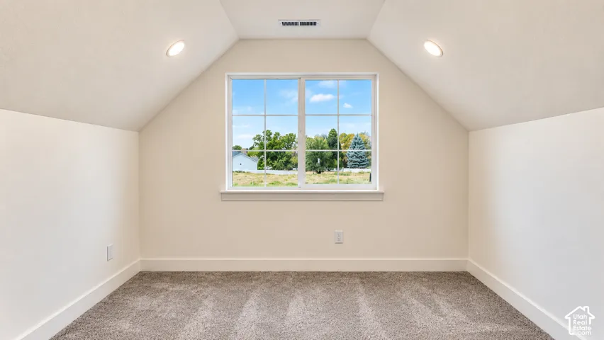 Vaulted ceiling, neutral wall tones, inset lighting, grid-pattern window, and carpeted flooring