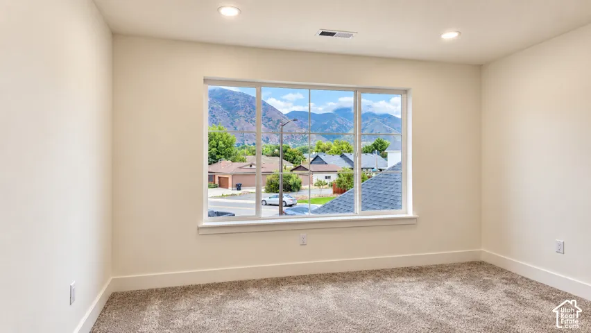 Neutral-toned interior featuring large picture windows, recessed lighting, and wall-to-wall carpeting, complemented by a prominent mountain backdrop