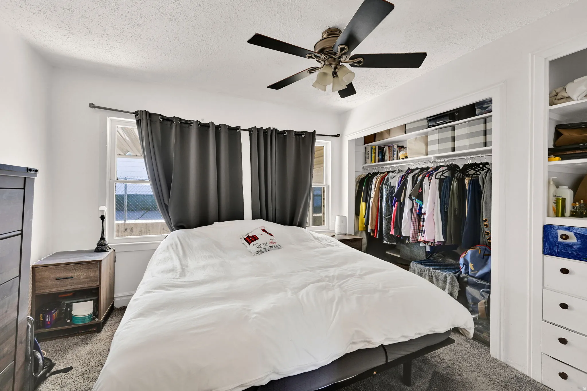 Bedroom featuring a ceiling fan with integrated lighting, two windows, and built-in closet shelving