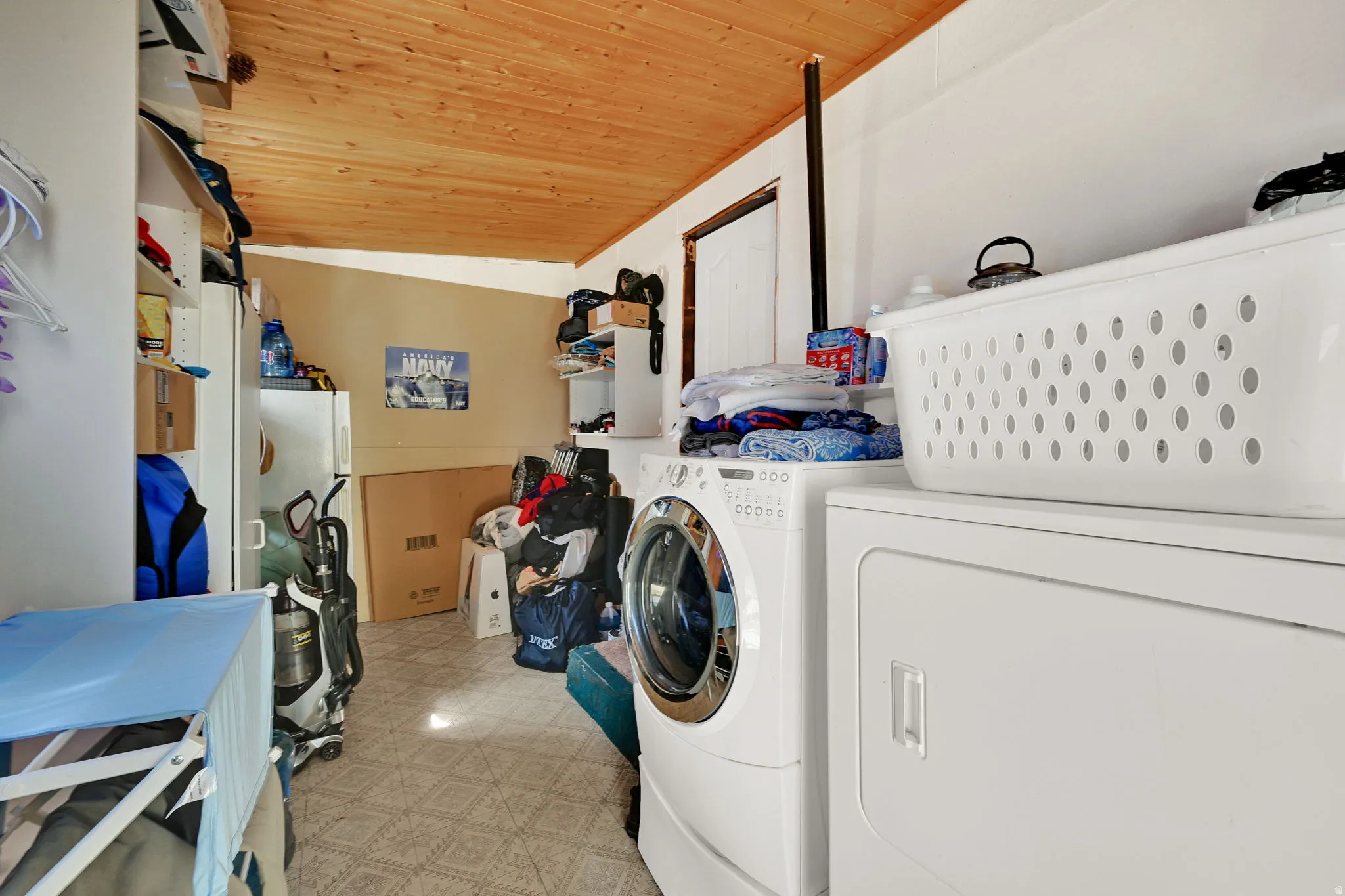 Laundry area featuring a wood-panel ceiling, light-colored flooring, and white walls