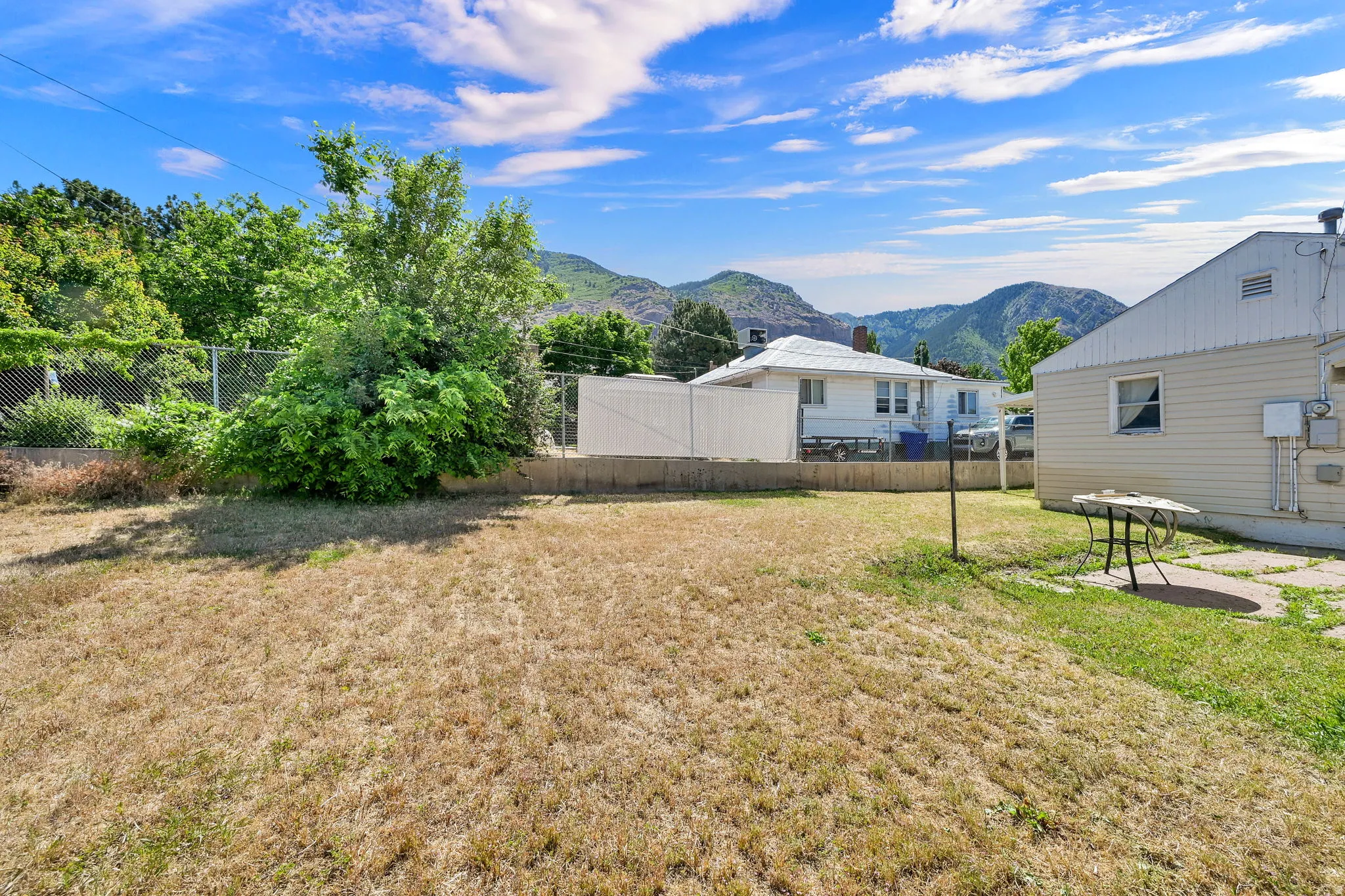 Expansive outdoor space featuring a large lawn area and established perimeter fencing