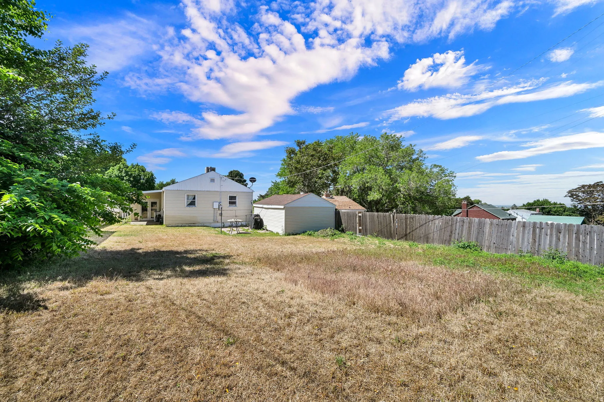 Expansive rear yard featuring a detached storage shed and wood privacy fencing