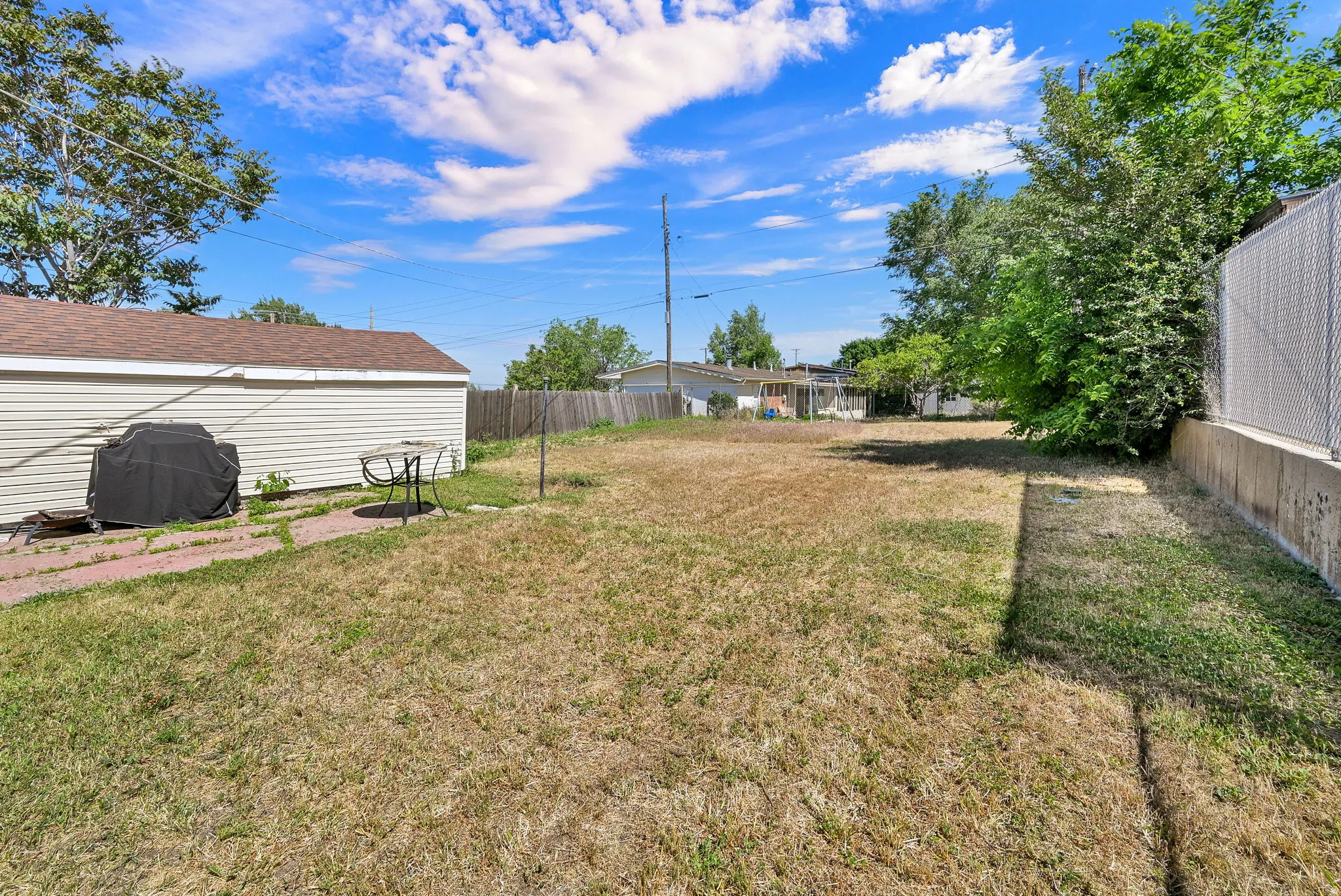 Expansive grassy lot with mature perimeter trees and a concrete retaining wall