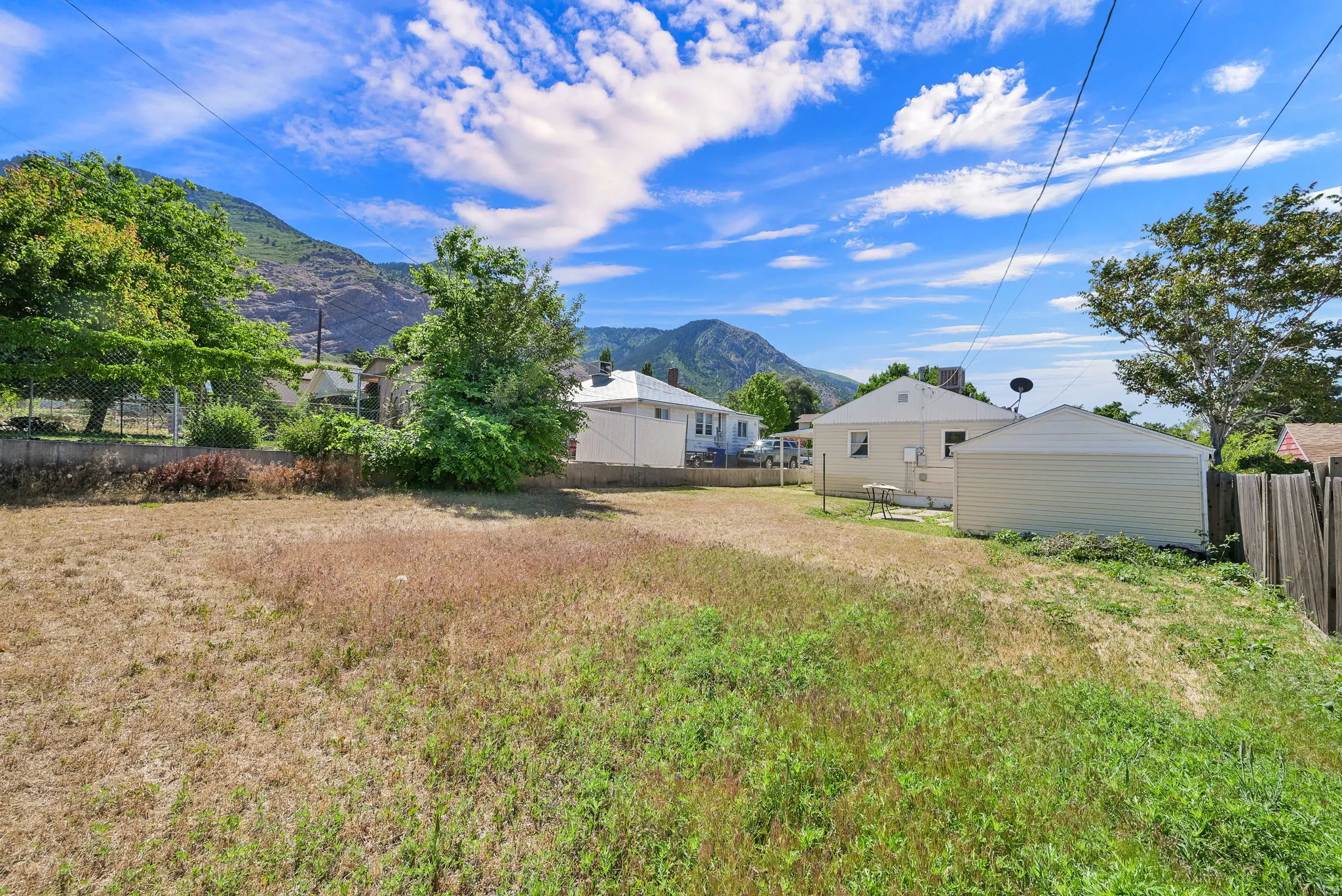 Expansive outdoor area featuring varied natural ground cover and mature perimeter trees
