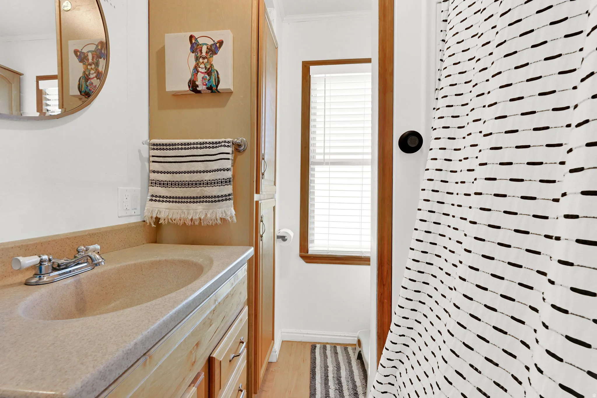 Bathroom featuring a vanity with a beige solid surface countertop and integrated sink, a chrome two-handle faucet, and light wood-finish cabinetry