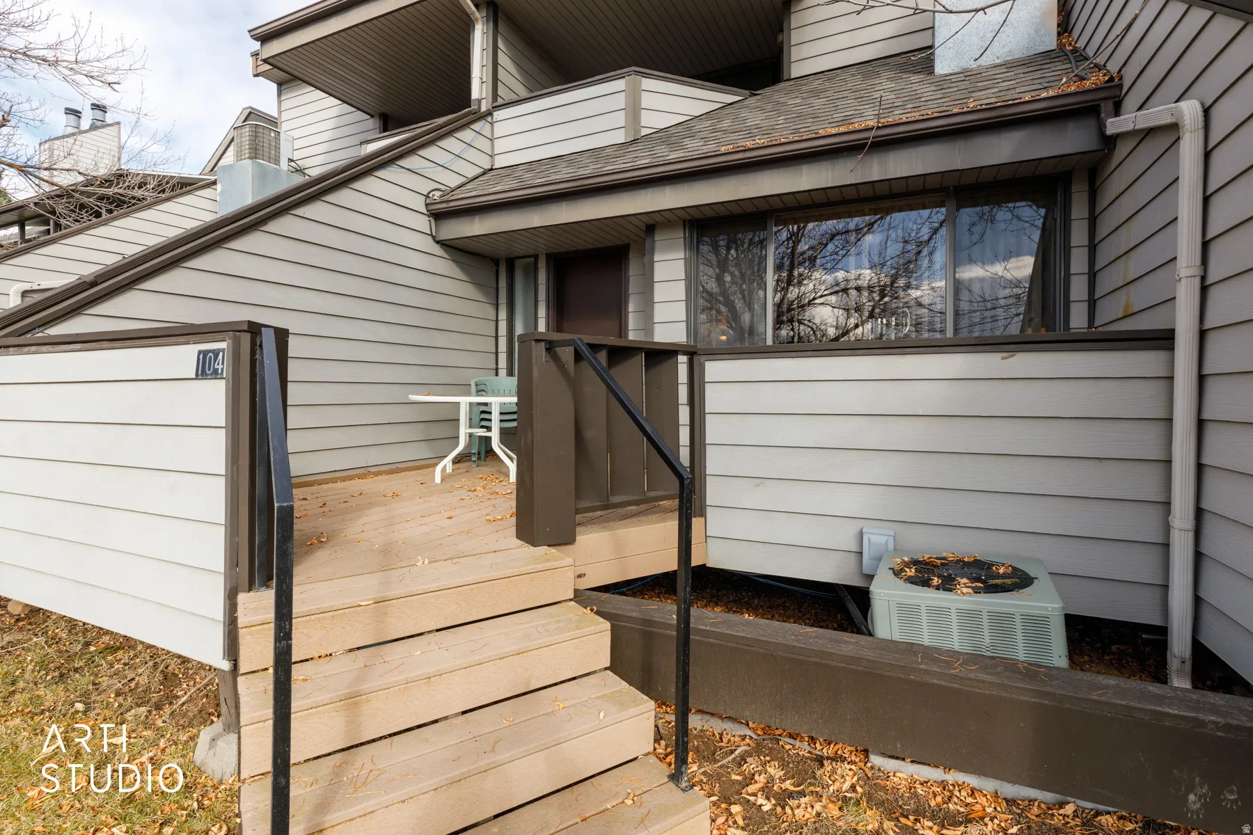 Multi-level townhouse exterior featuring light gray horizontal siding, dark trim, and a shingled roof