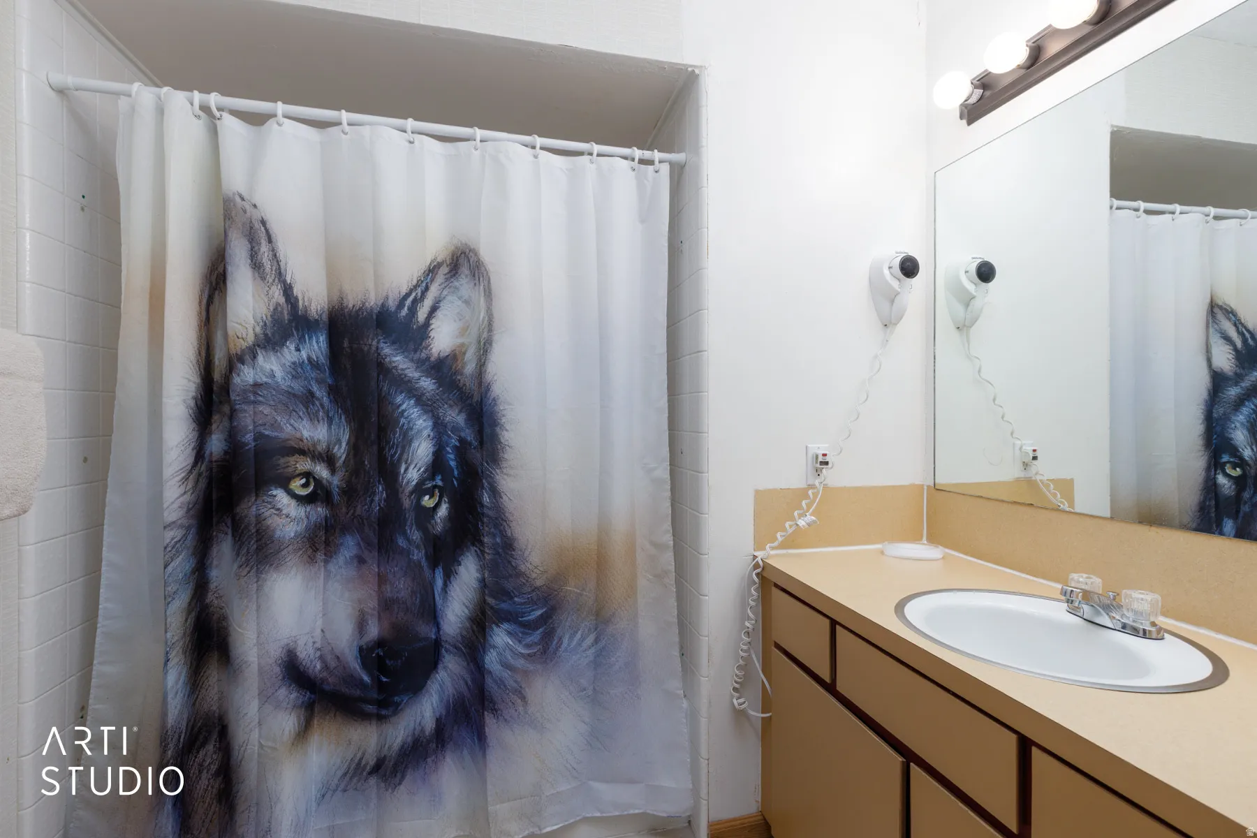 Bathroom featuring a single vanity with a laminate countertop, an integrated sink with a chrome faucet, and a large wall-mounted mirror with overhead bar lighting
