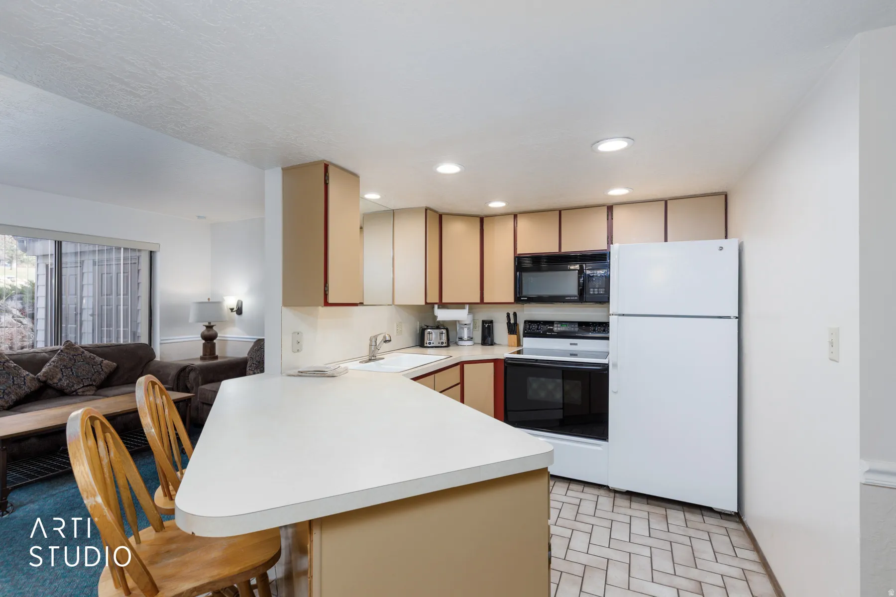 Kitchen featuring herringbone-patterned tile flooring, recessed lighting, white appliances, and a breakfast bar