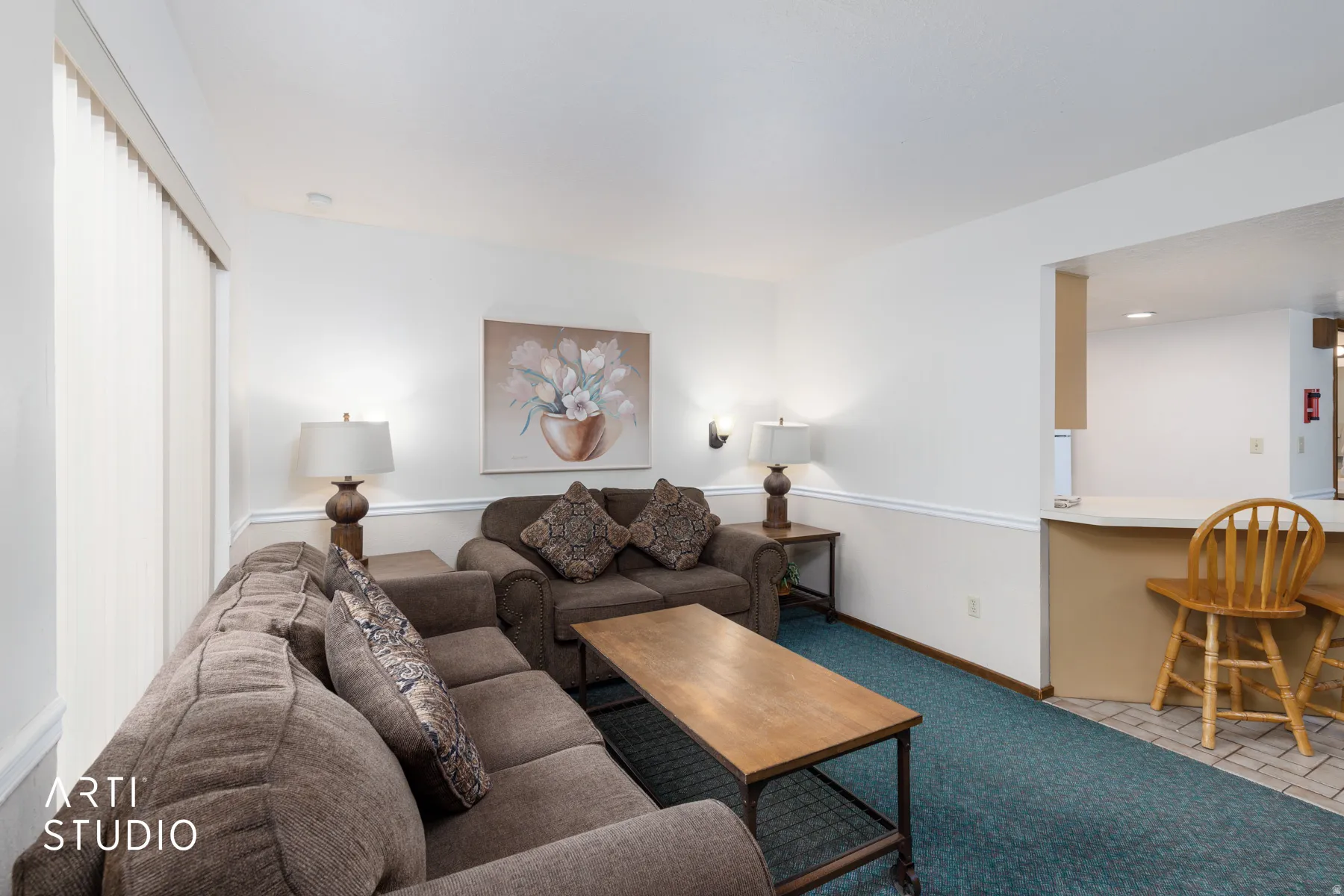 Living area featuring a textured carpet flooring and white walls with chair rail molding