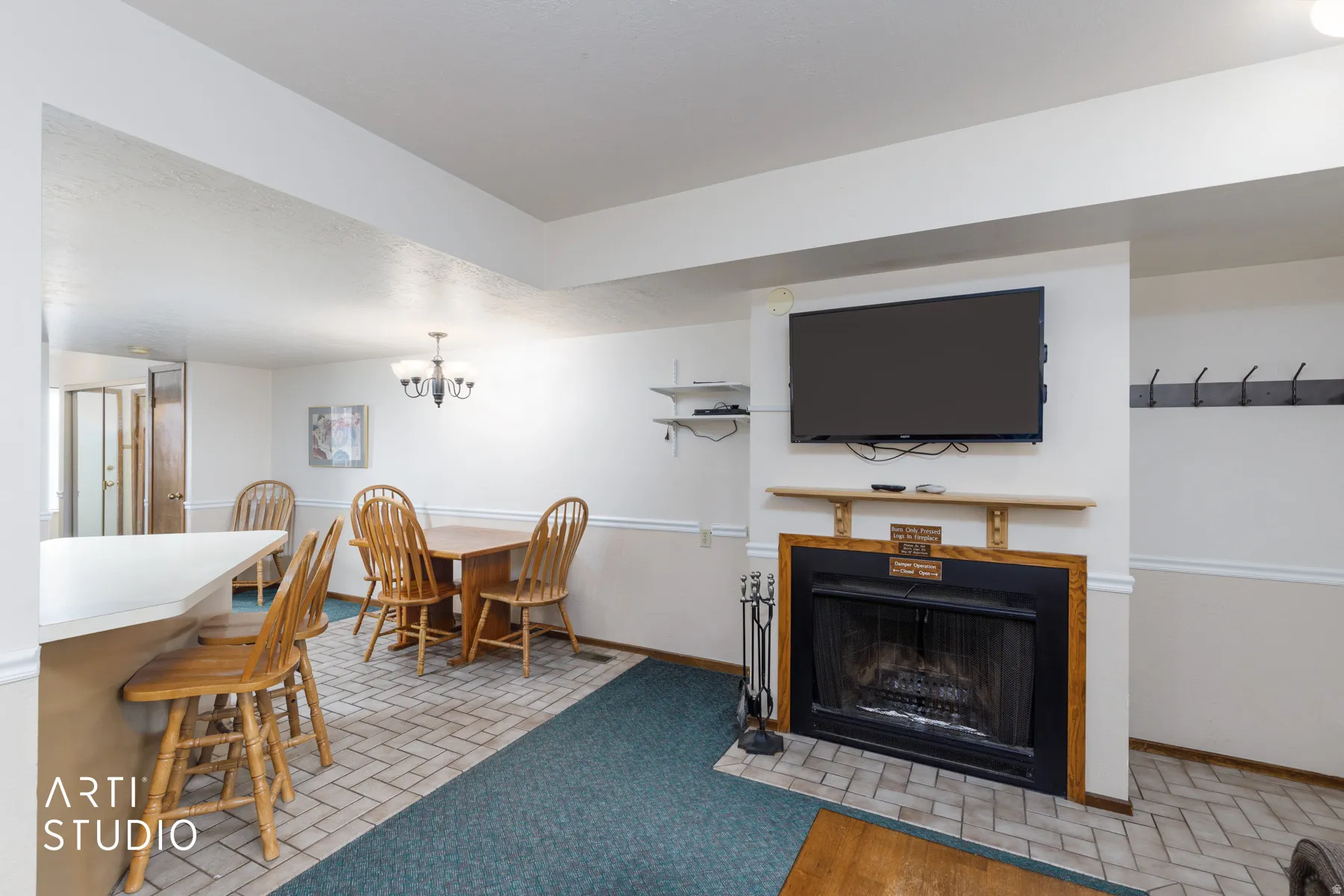 Living area featuring a black fireplace with a wood mantle, a white breakfast bar, recessed lighting, and a chandelier