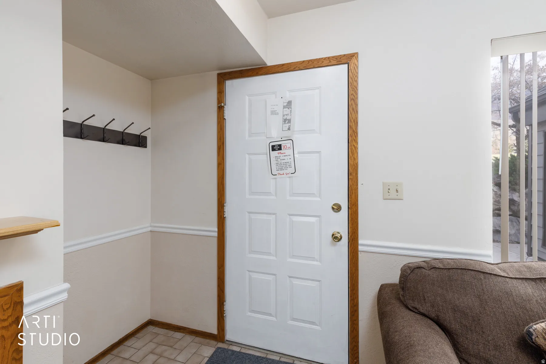 Entryway featuring a paneled door with wood trim, a coat rack, and tiled flooring