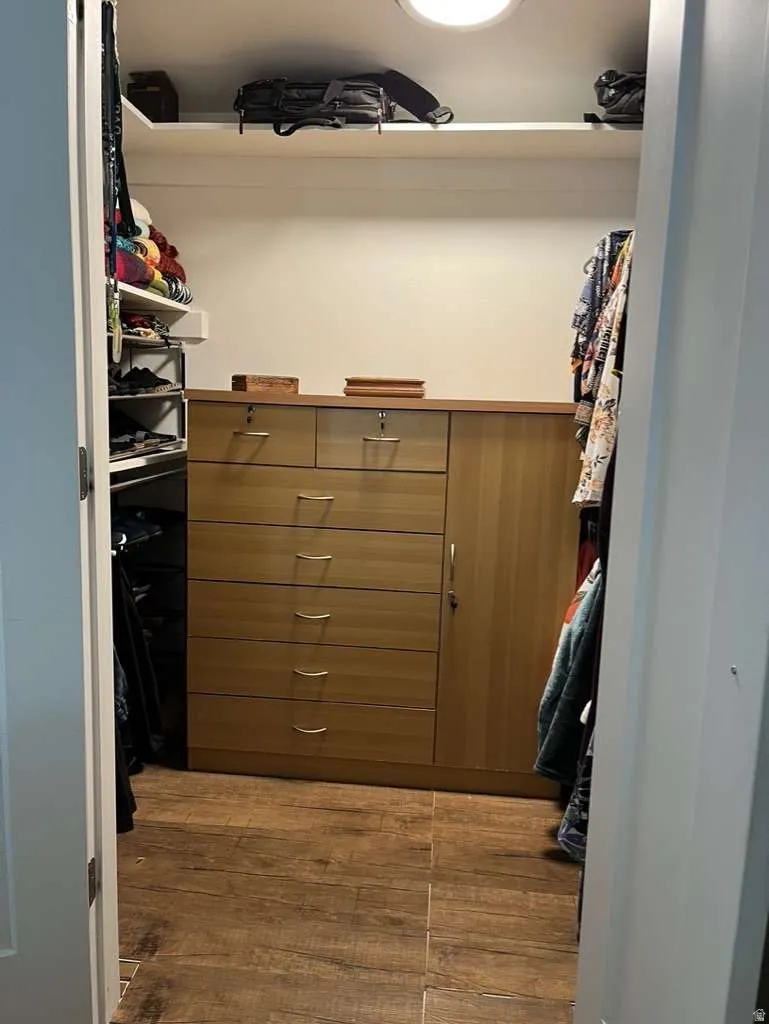 Custom closet system featuring wood-finish flooring, built-in drawers with metal hardware, and integrated shelving