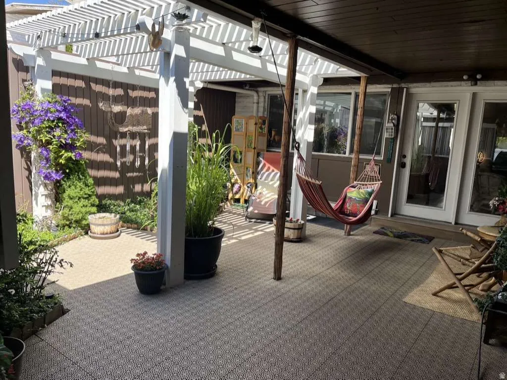 Outdoor patio area featuring a white slatted pergola and patterned tile flooring