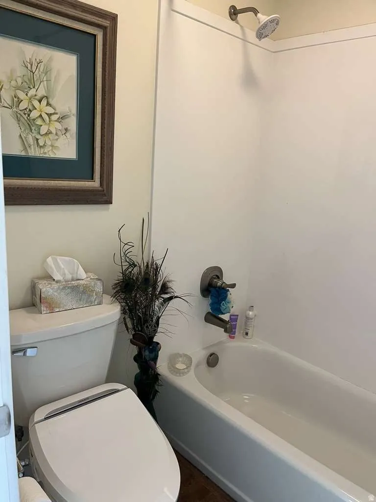 White bathtub with brushed nickel fixtures and a white shower surround