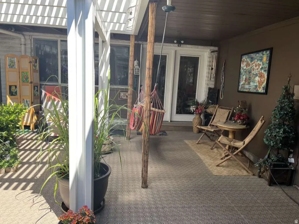 Covered patio featuring a slatted pergola roof and outdoor carpeting