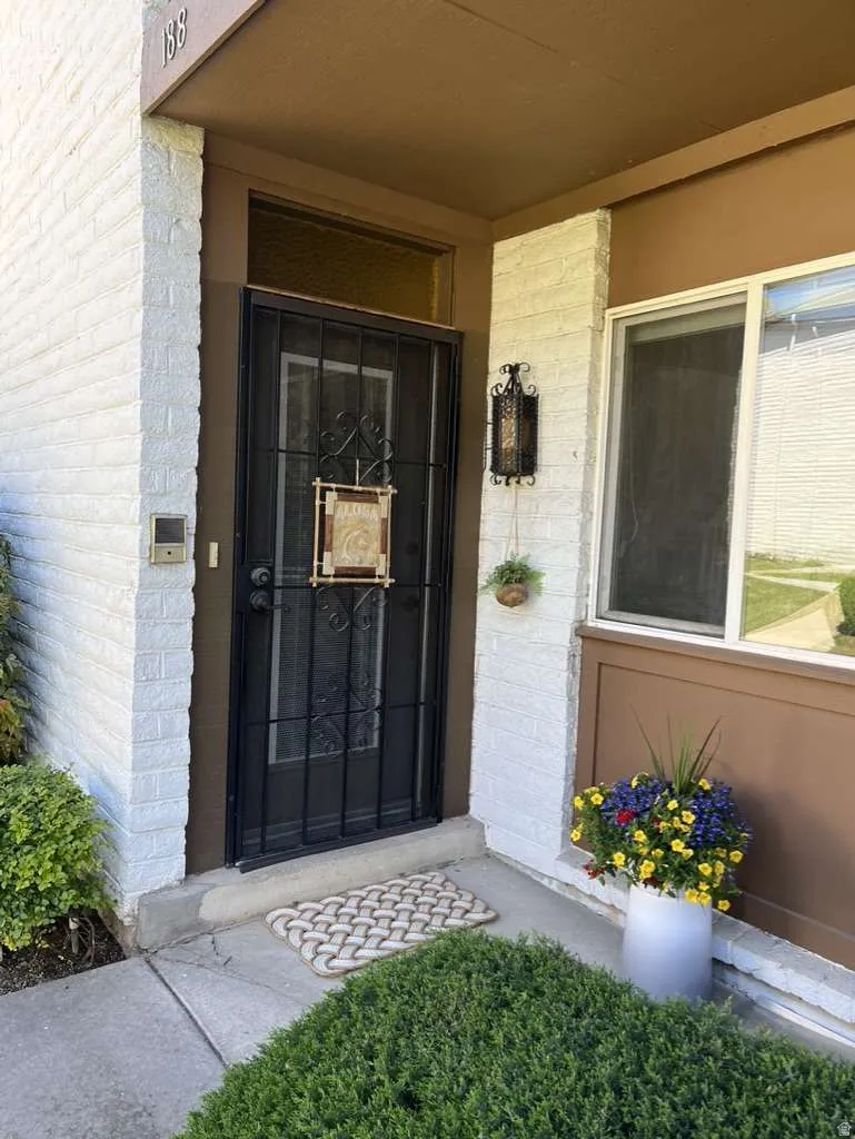 Entryway featuring white painted brick, a security screen door, and a transom window