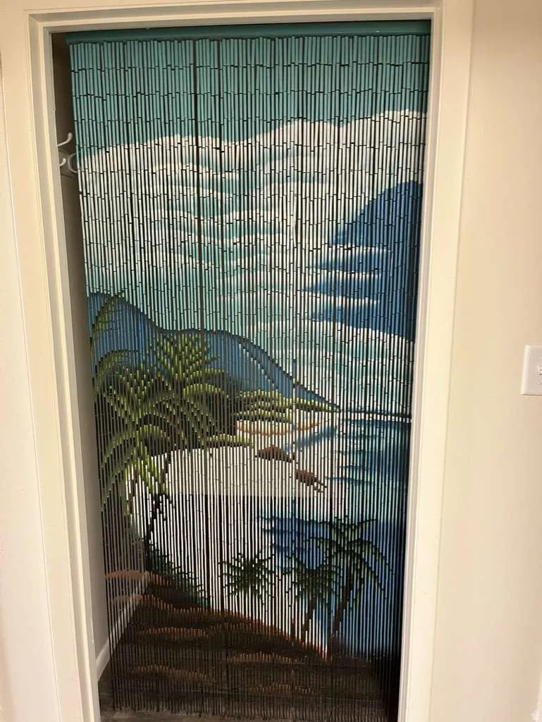 Beaded curtain featuring a tropical landscape design with palm trees and a water scene