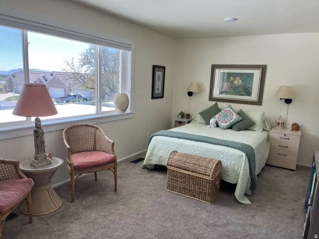 Spacious room featuring broad windows with white trim, wall-mounted sconces, and neutral-toned carpeting