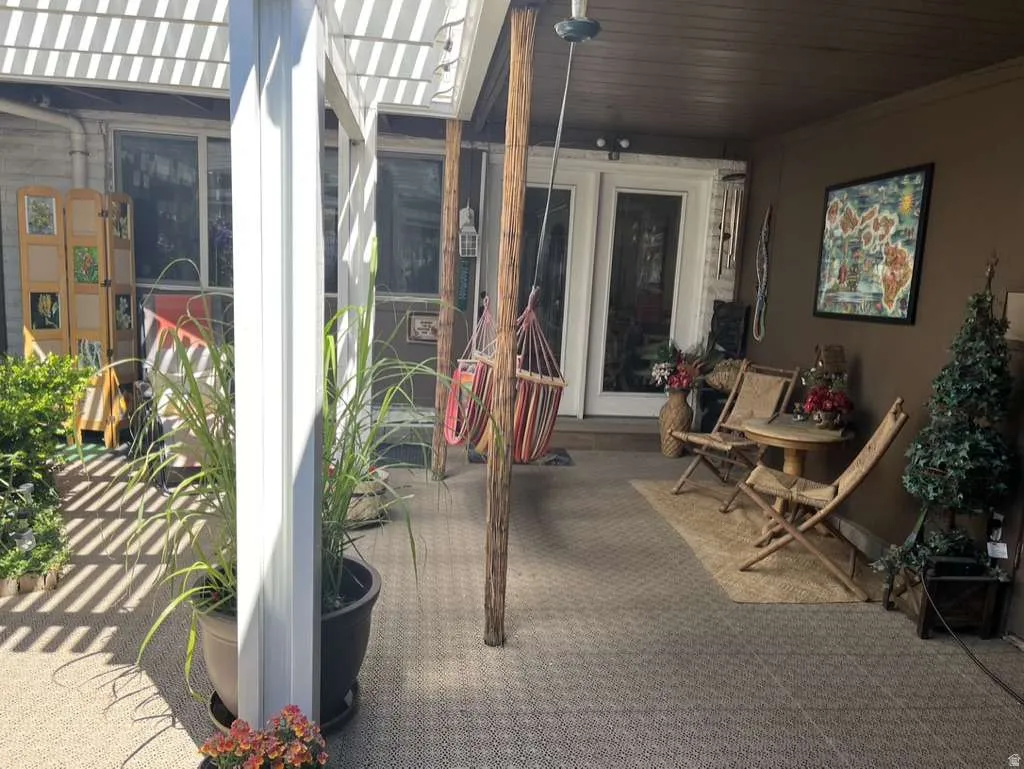 Shaded patio featuring a lattice pergola, textured outdoor flooring, and access to the interior via double glass doors