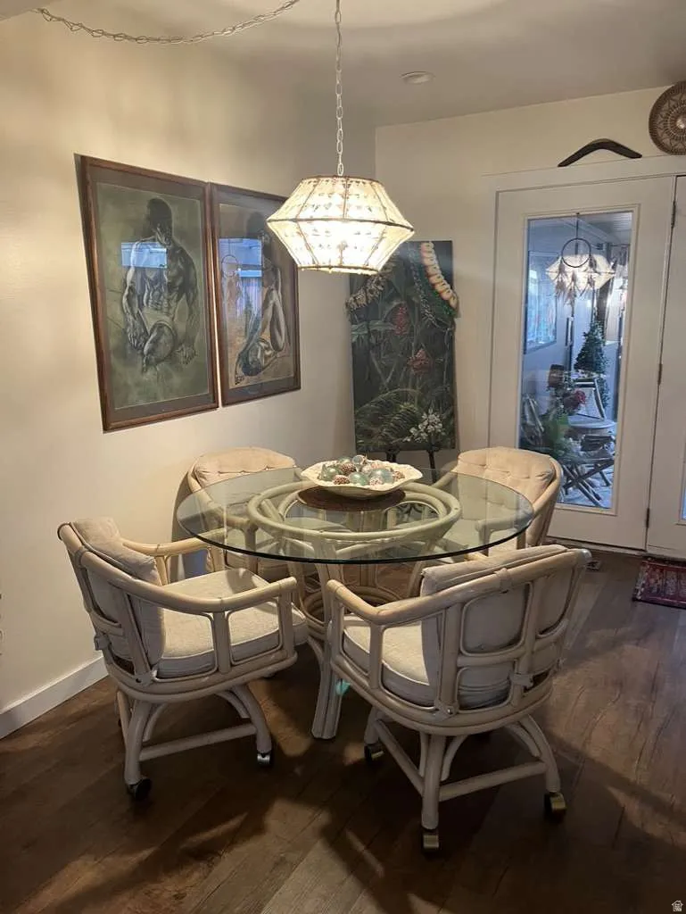 Dining area featuring dark wood-finish flooring, a glass-top table, and a glass-paneled door