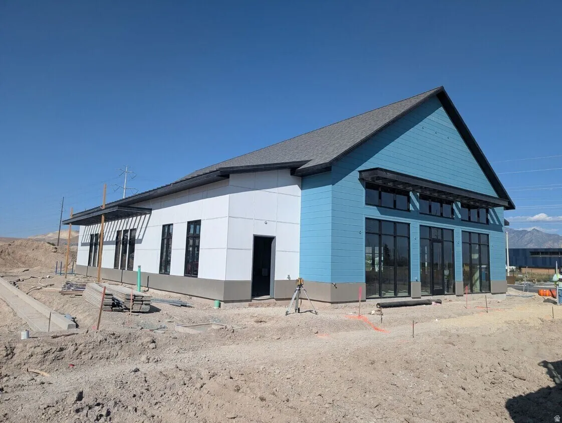 Modern structure featuring a pitched roof, light blue and white panel siding, and large black-framed windows