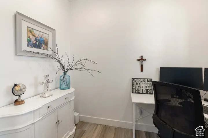 Office space featuring light-toned wood-finish flooring and white baseboards