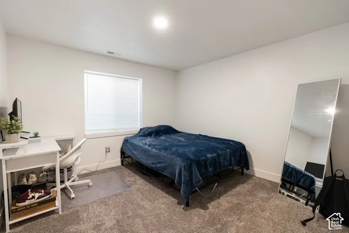 Carpeted room featuring a white-trimmed window with blinds, white walls, and an overhead light fixture