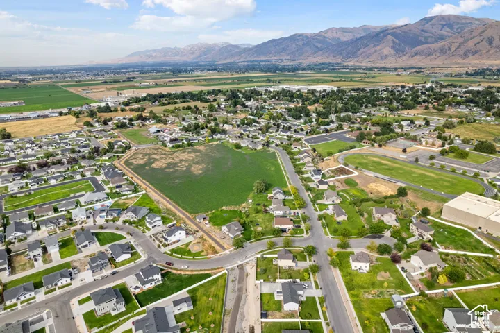 Expansive aerial perspective showcasing a residential development with surrounding green spaces and distant mountain ranges
