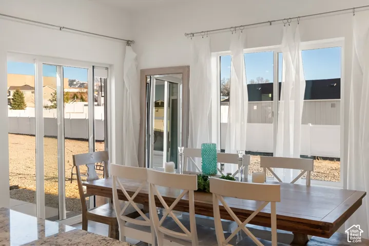 Bright dining area featuring a sliding glass door and multiple windows providing outdoor access and natural illumination