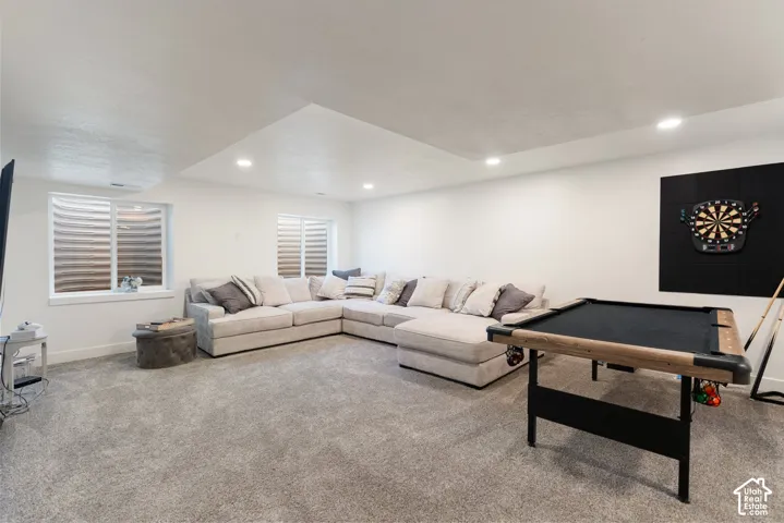 Spacious entertainment area featuring recessed lighting and light gray carpeting