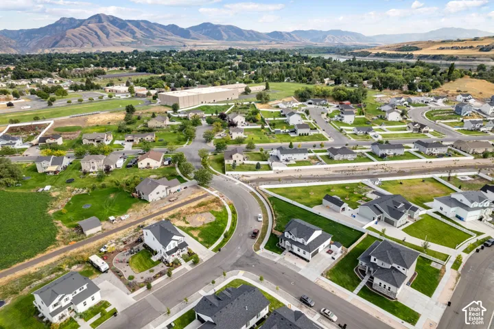 Aerial perspective showcasing a residential community with contemporary homes, mountain backdrop, paved streets, and green spaces