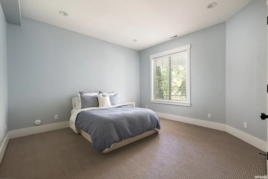 Carpeted room featuring a wide window with white blinds, recessed lighting, and crisp white baseboards