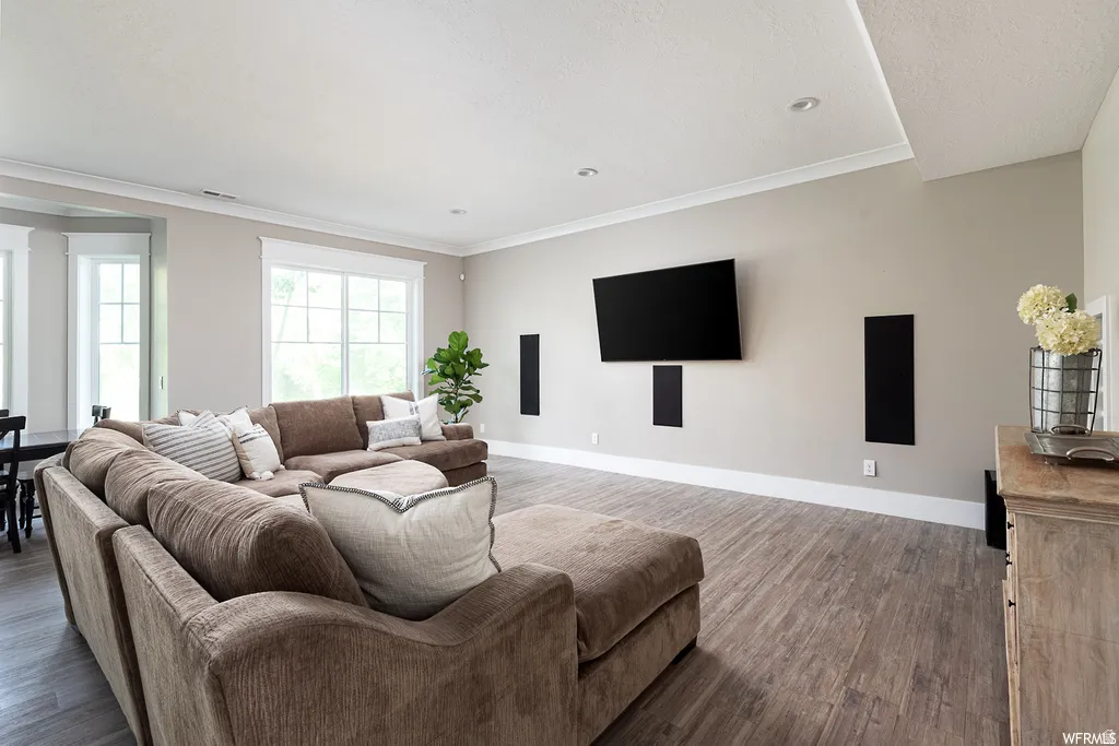 Spacious living area featuring wood-finish flooring, recessed lighting, and crown molding