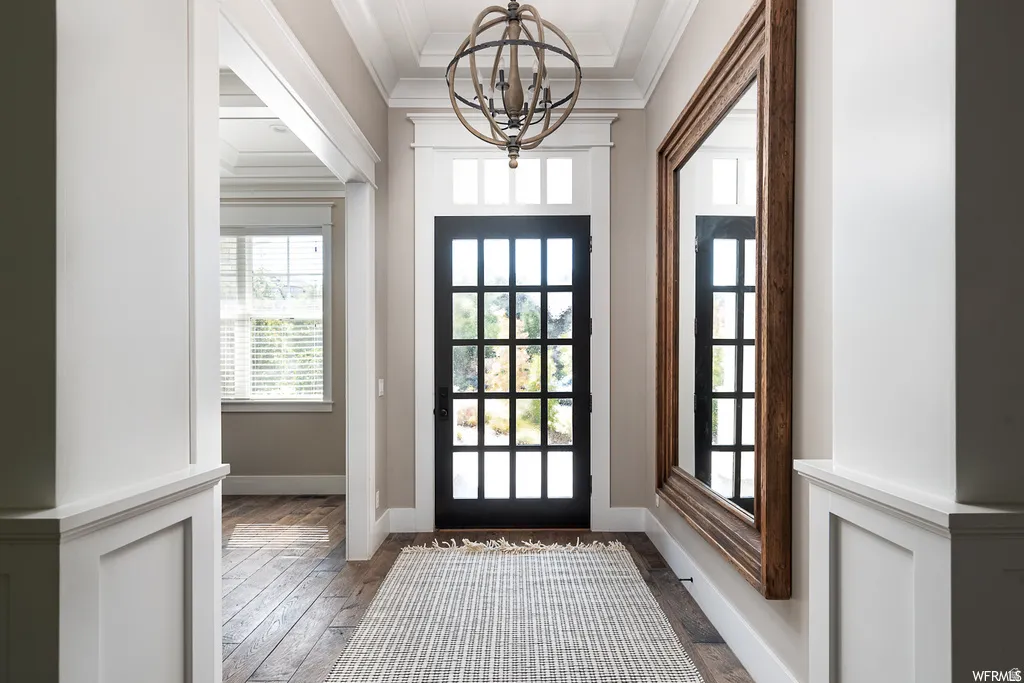 Entryway featuring a grid-paneled front door with transom window, wood-finish flooring, white wainscoting, and a spherical chandelier