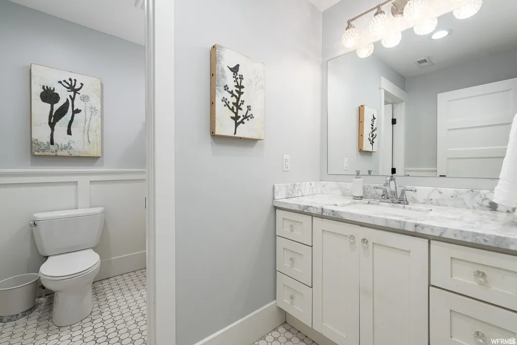 Bathroom featuring a white vanity with marble-finish countertop, clear knob hardware, and a framed mirror