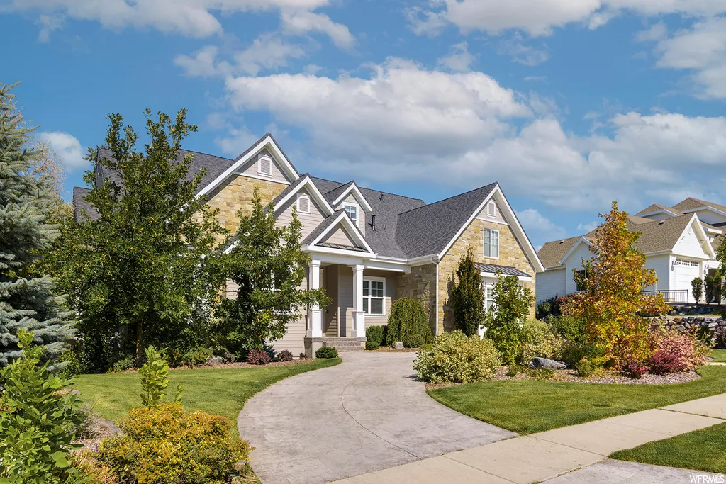 Stone and siding exterior with multiple gables and a dark shingle roof