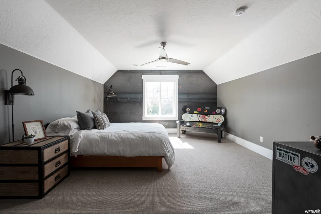 Attic room with sloped ceilings, a single window, and textured gray carpeting