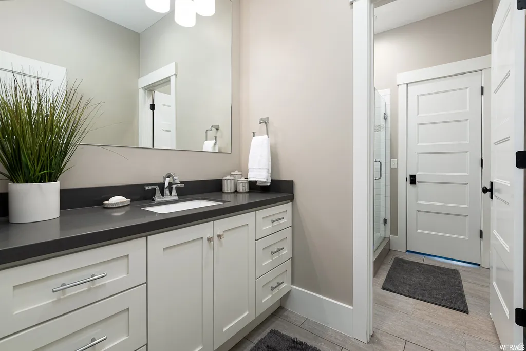 Bathroom featuring a vanity with white cabinetry, a dark countertop, and a rectangular undermount sink