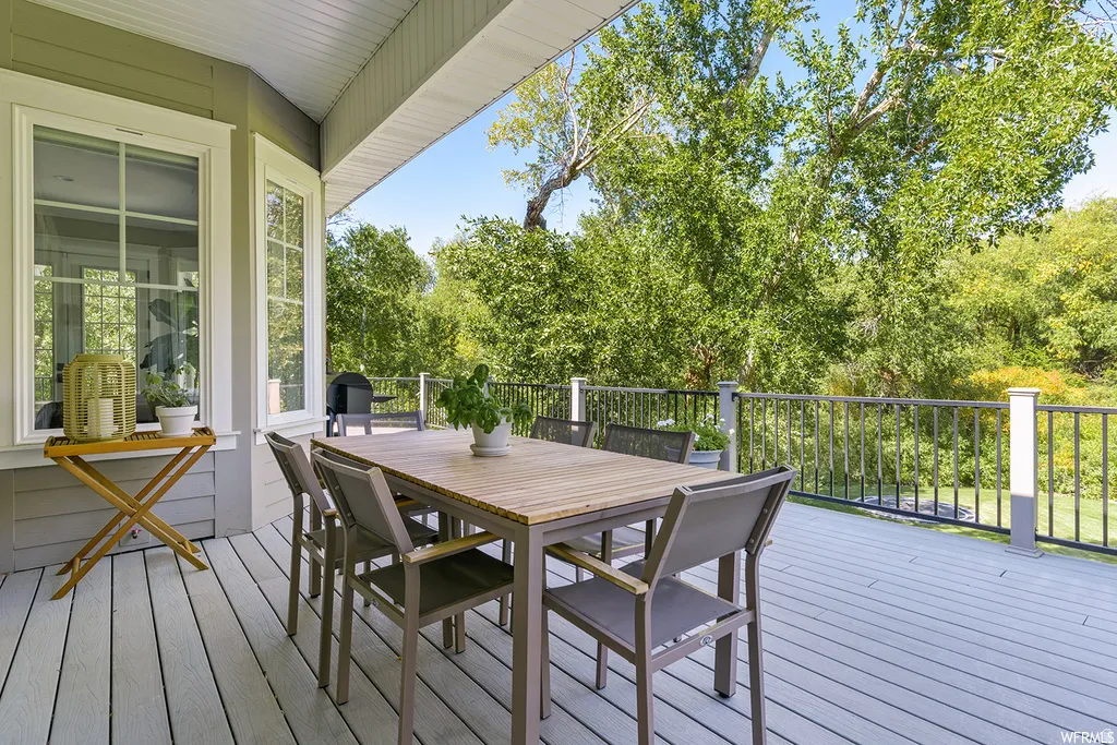 Covered outdoor deck featuring composite decking, gray siding, and a black metal railing