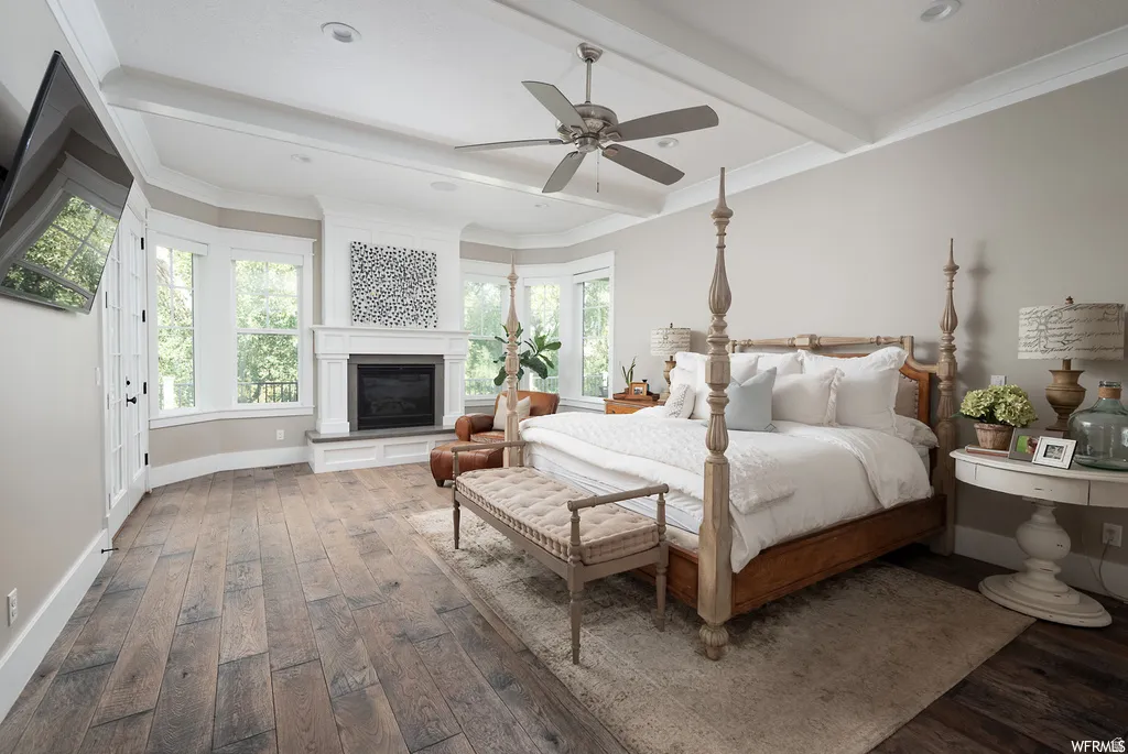 Expansive room featuring wood-finish flooring, a ceiling fan, and decorative tray ceiling