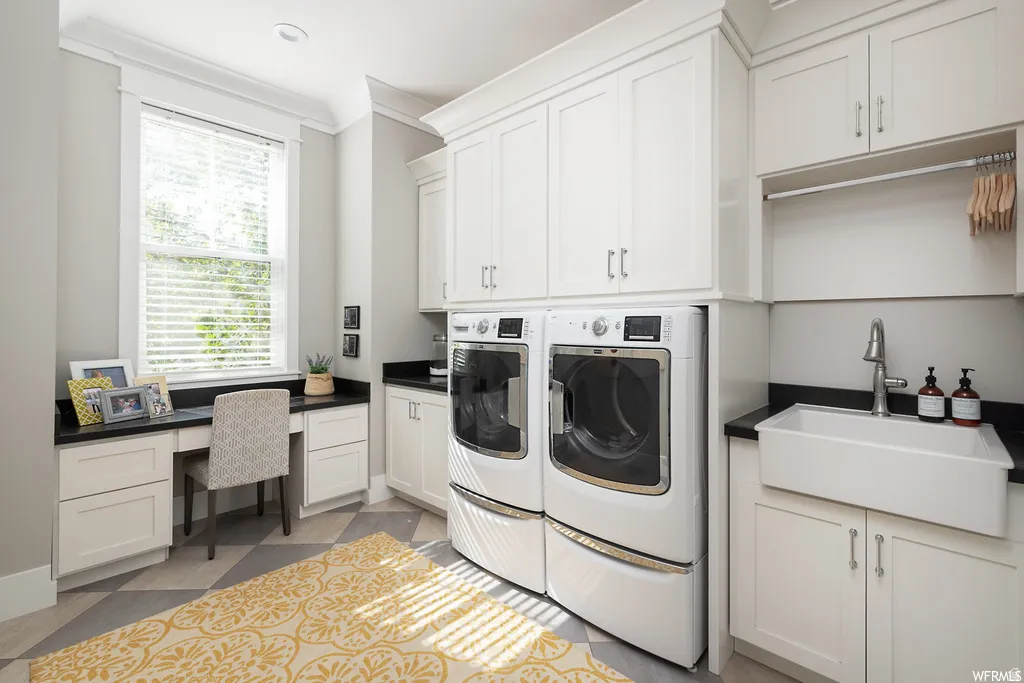 Laundry room featuring white cabinetry, black countertops, a built-in desk, a deep utility sink, and diamond-patterned flooring