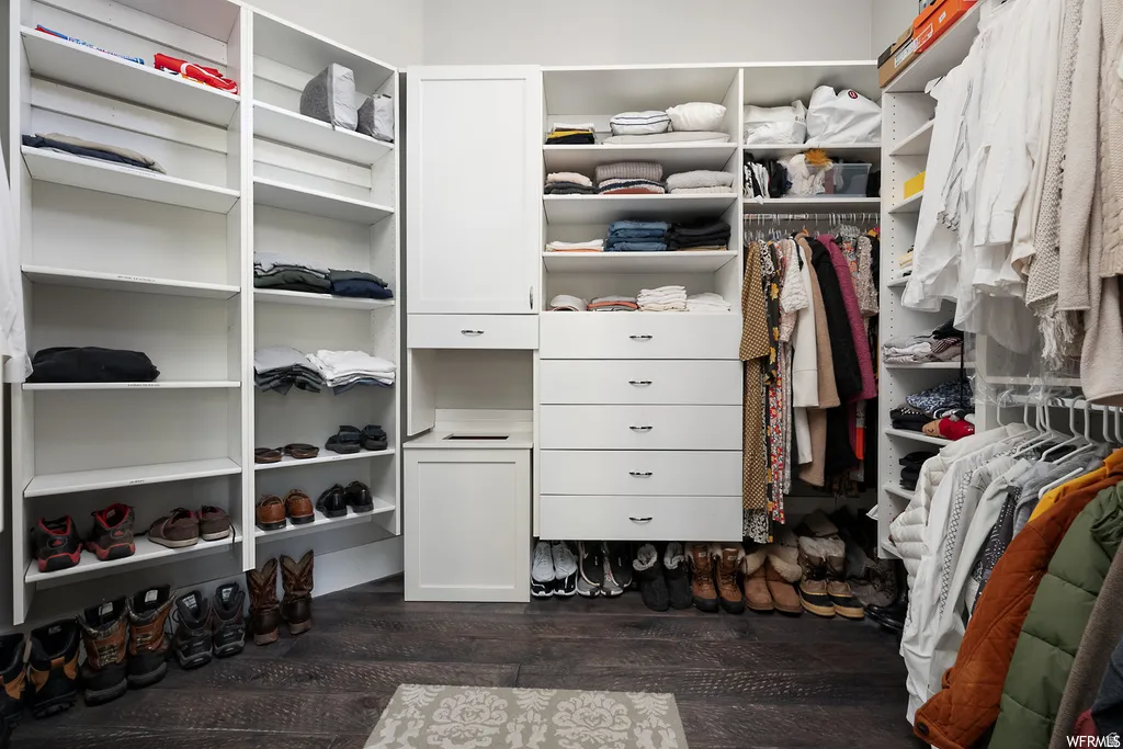 Custom-built white storage system featuring multiple shelving units, hanging rods, integrated drawers, and cabinet storage