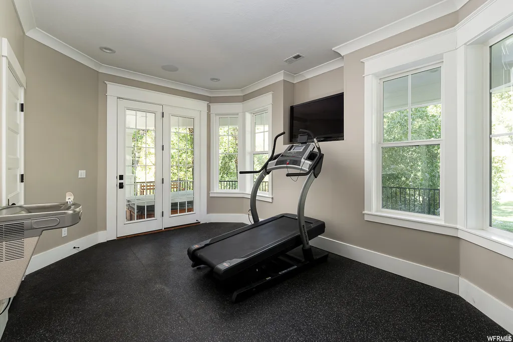 Interior space featuring black rubber flooring, double French doors, a built-in water fountain, and multiple windows with white trim