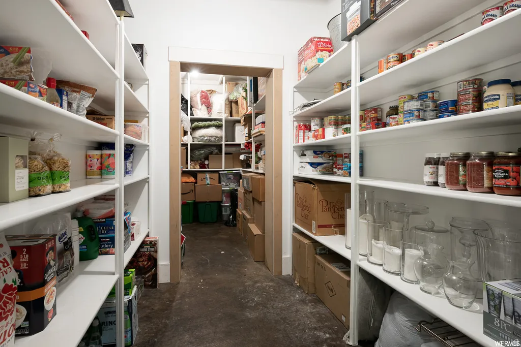 Spacious walk-in pantry featuring extensive built-in shelving, white painted finishes, and a durable flooring surface