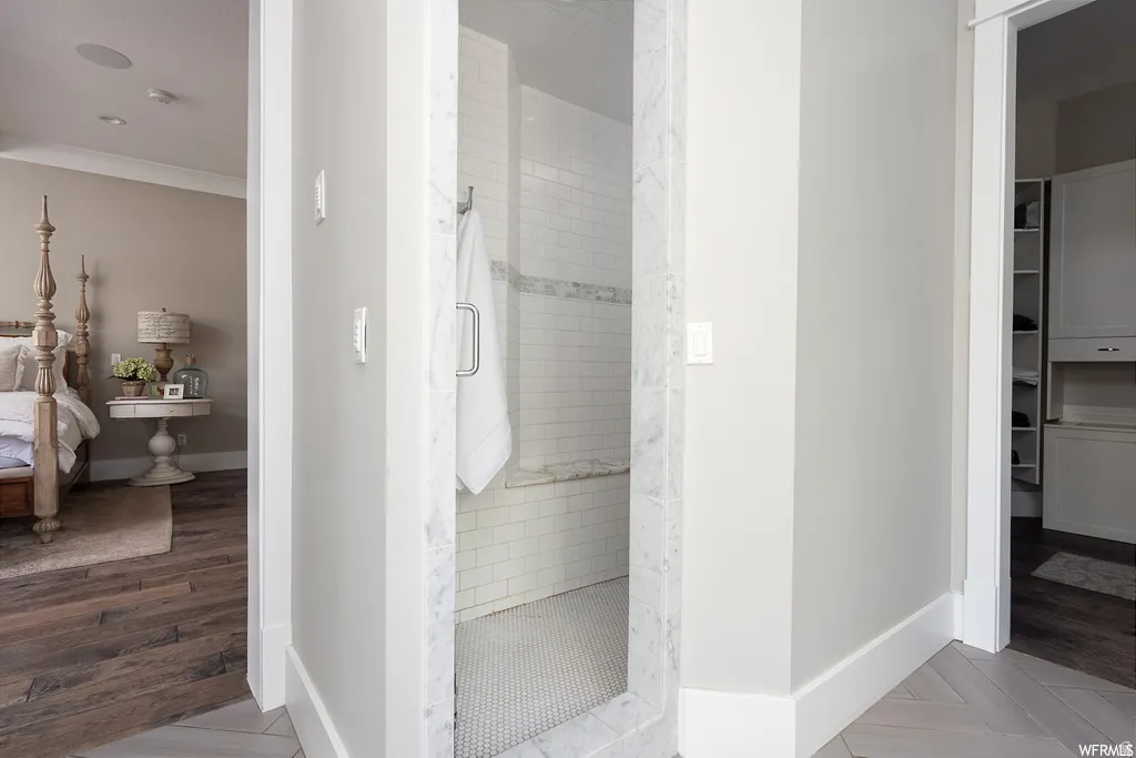 Spacious walk-in shower with subway tile, mosaic tile flooring, and a marble bench