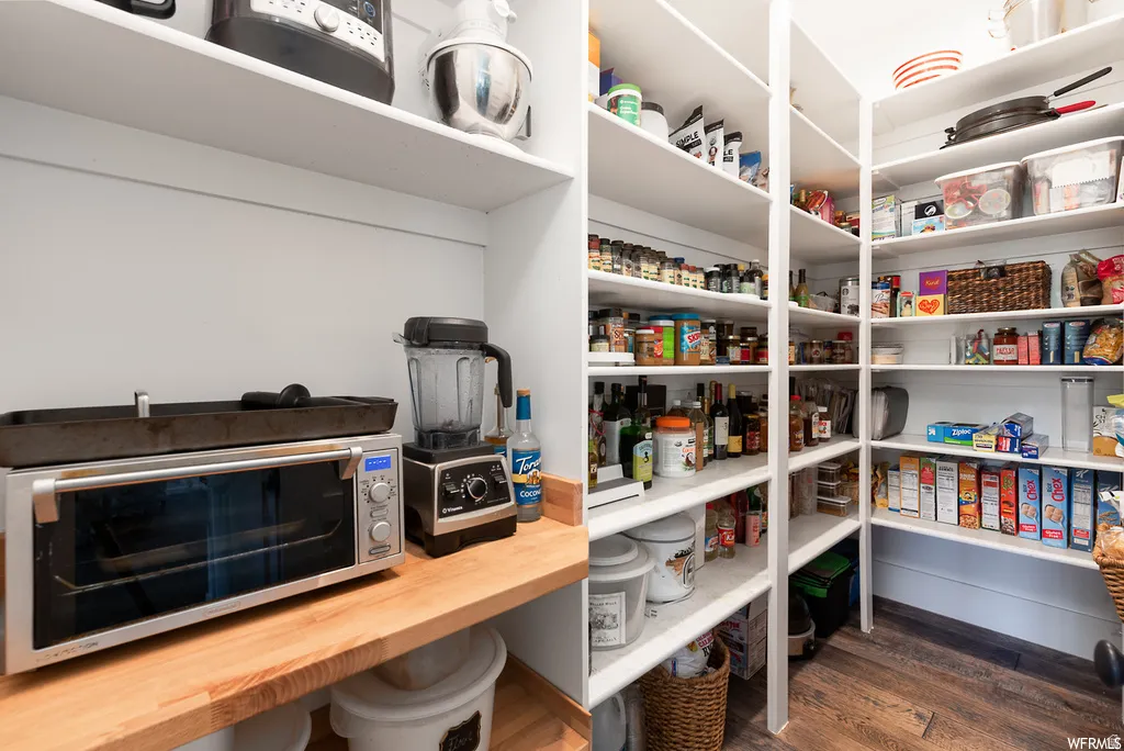 Walk-in pantry featuring extensive white shelving, wood-finish flooring, and a butcher block countertop