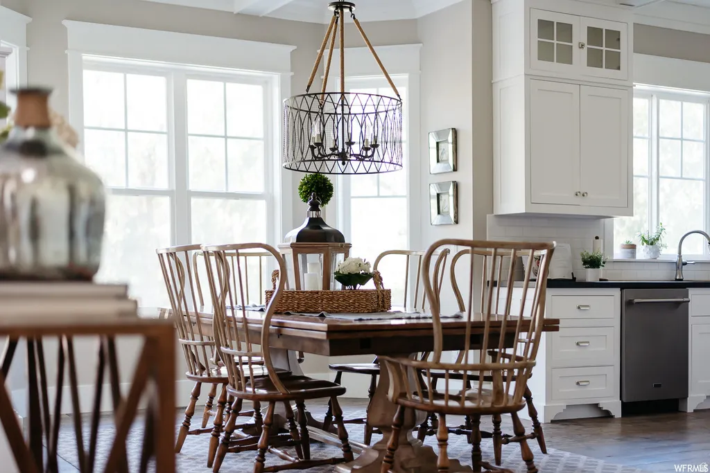 Dining area featuring a decorative chandelier, multi-pane windows with white trim, and a built-in kitchen cabinet system with stainless steel appliances