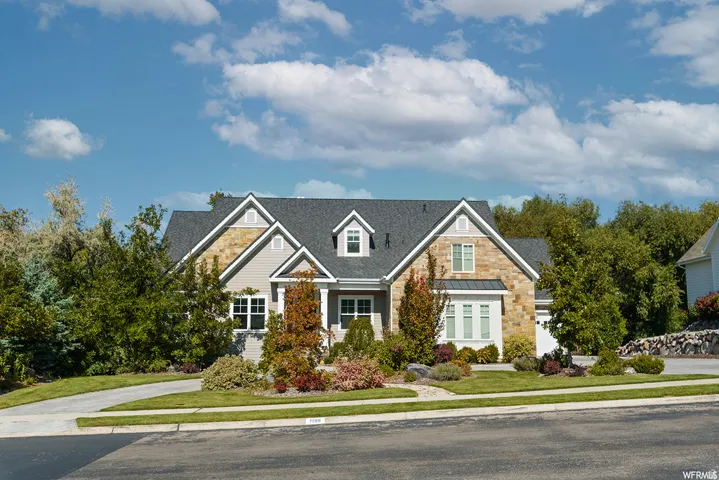 Two-story residence featuring a stone and siding facade, a dark shingle roof, and multiple gables